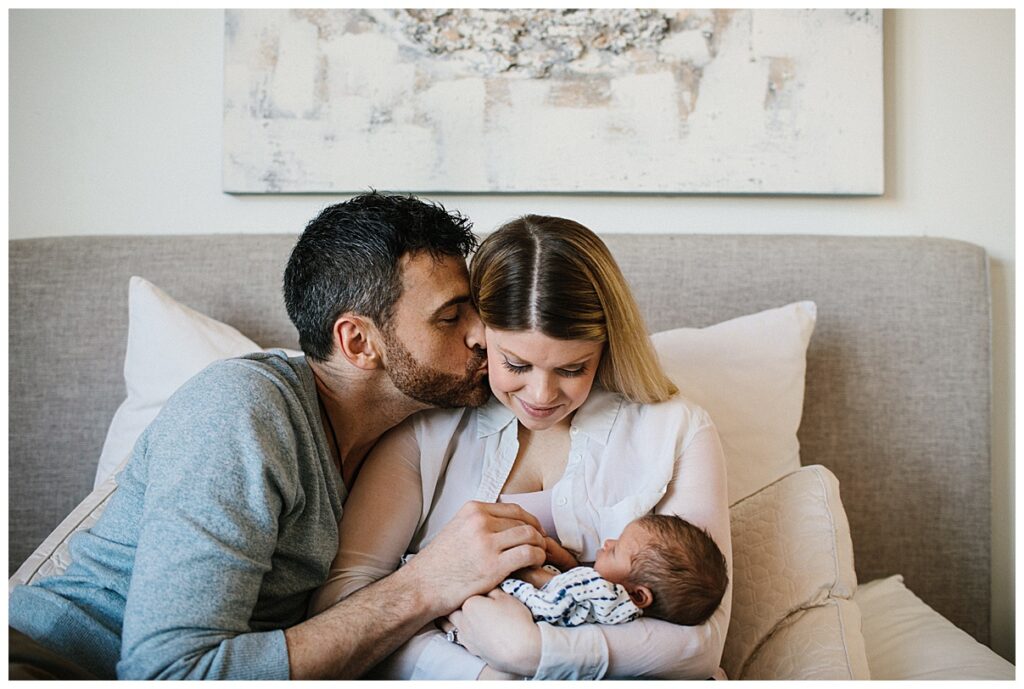 Mom, Dad, and Baby snuggle on the bed! Top 3 tips your newborn for their Lifestyle Newborn Session with Emily Louise Photography in Fort Wayne Indiana